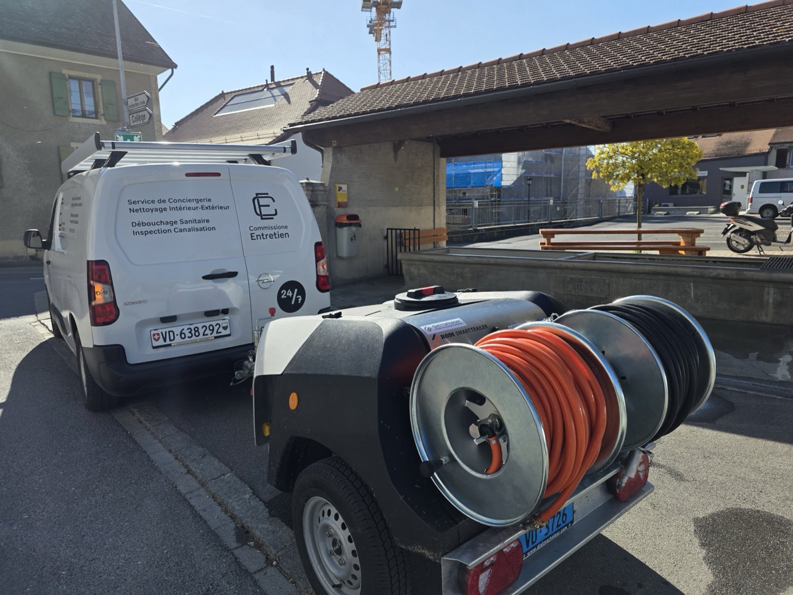 Fourgon Commissione Entretien attelé à sa remorque de curage, sur une place de village